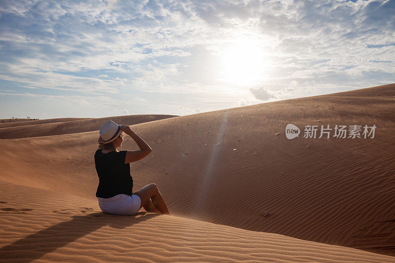 一个女人赤脚站在沙漠的沙丘上