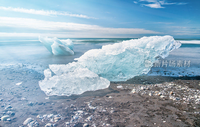 阳光明媚的冰岛Jokulsarlon钻石海滩上的冰山。长时间曝光与流动的水