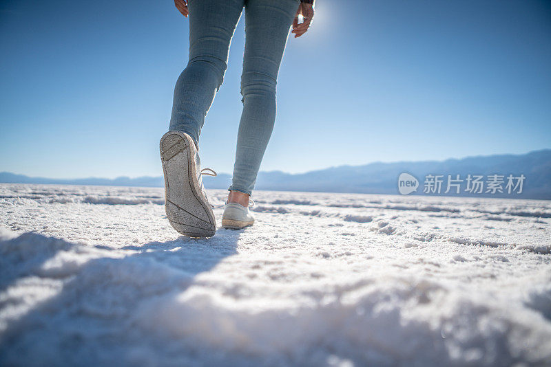 年轻女子站在沙漠的盐滩上凝视壮观的风景;女孩旅行，发现世界