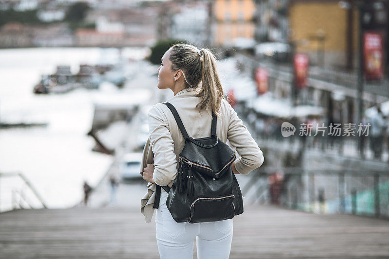 年轻女子背着背包走在葡萄牙波尔图市的街道上