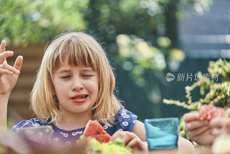 小女孩在外面的花园里吃新鲜的西瓜