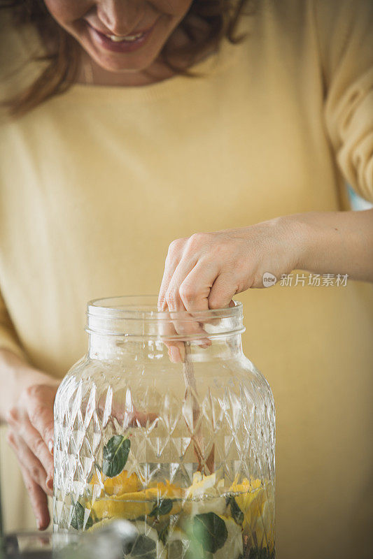 女人在搅拌蜂蜜到柠檬水里