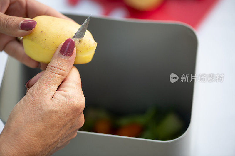 堆肥的概念。女人的手在有机废物桶里削土豆，用于回收和有机肥料