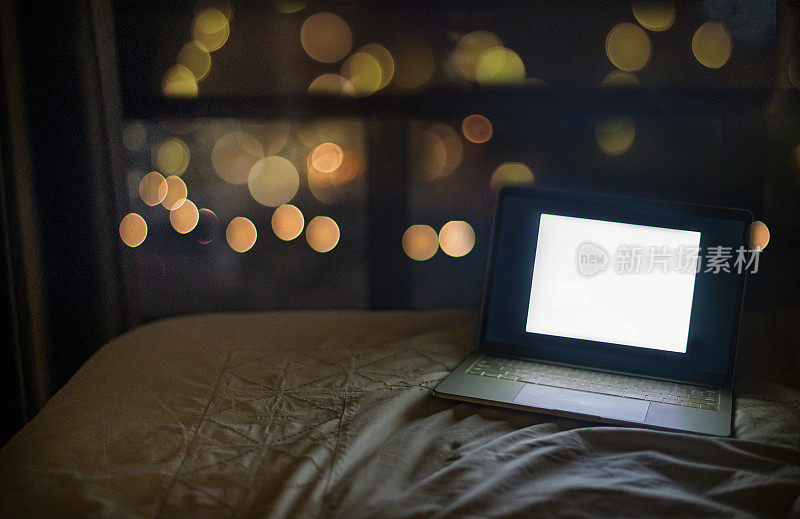 晚上打开床上的笔记本电脑，用散景模糊灯光图像