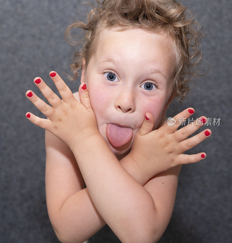 一个五岁白人女孩的肖像。女孩展示了她的舌头和指甲，指甲涂了红色。