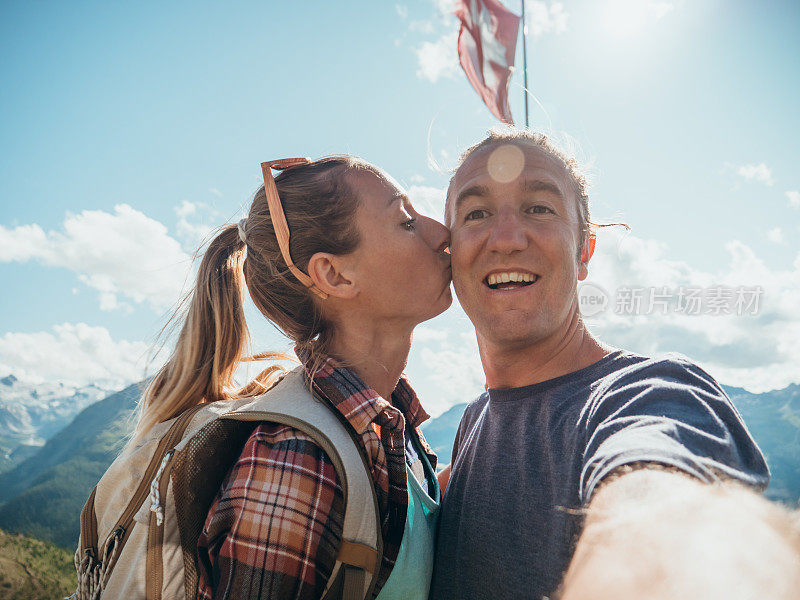 夫妇在山顶上举着瑞士国旗自拍