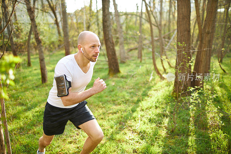 一位中年男子在森林里慢跑，伸伸懒腰，做健身训练