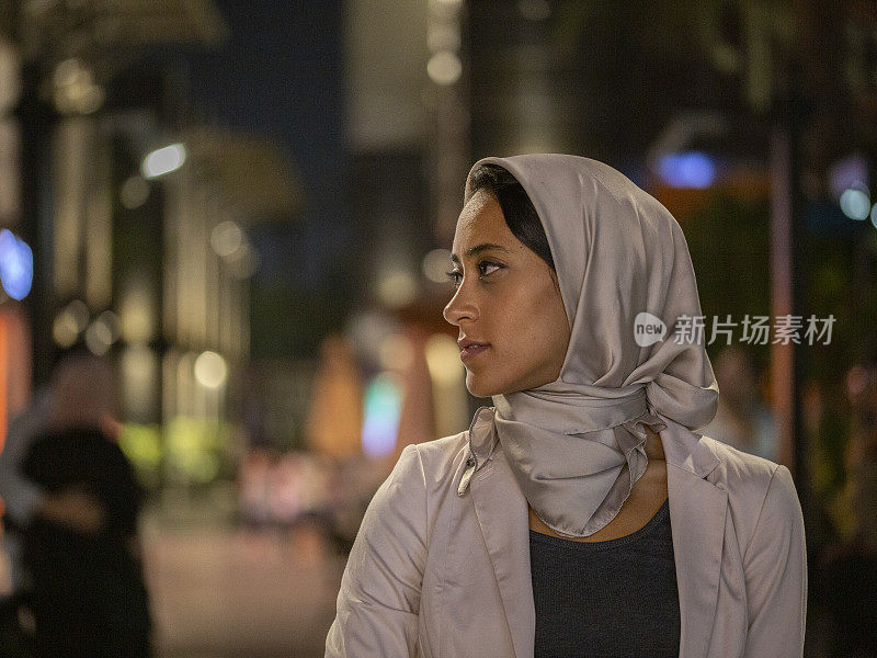 在灯火通明的城市里，中东妇女戴着头巾