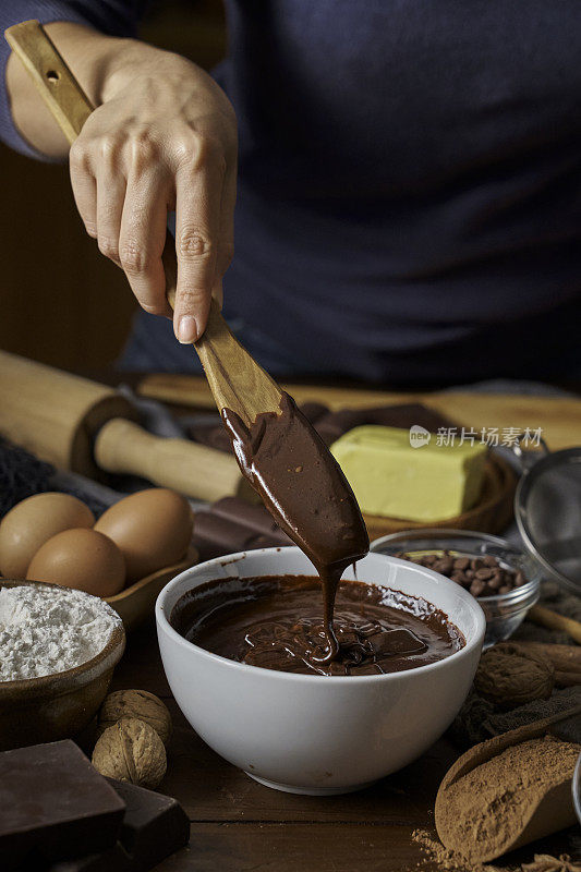 在一个乡村厨房的木桌上，女人用双手制作巧克力慕斯和饼干