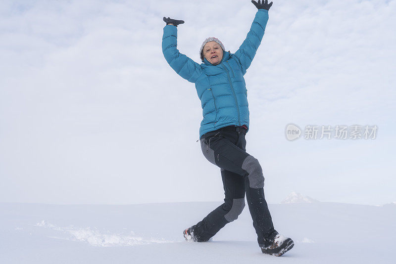 成熟的女人穿着皮大衣在雪地里奔跑