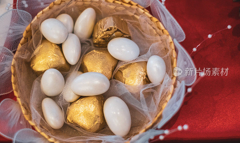 美丽的金色包装巧克力和白糖的礼物篮为圣诞节庆祝与装饰在红色的背景