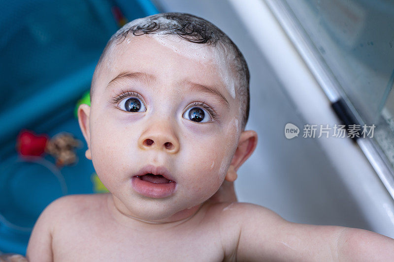 可爱的混血亚裔白种人婴儿男孩与大棕色眼睛在浴缸微笑
