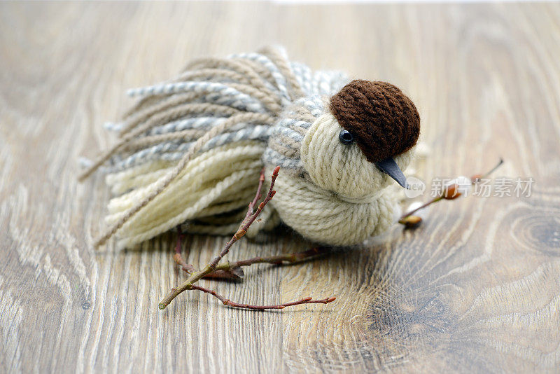 用羊毛制成的麻雀线鸟栖息在小树枝上