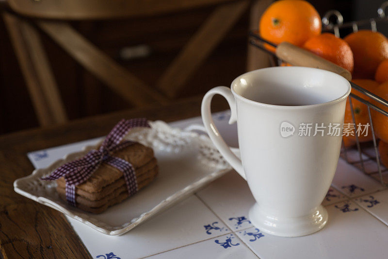 一杯茶，茶壶，饼干和橘子在桌子上-库存照片