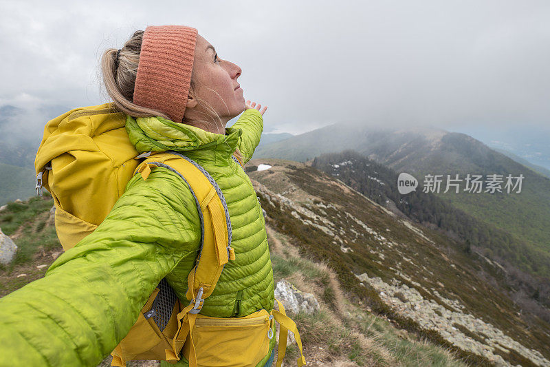 一个徒步旅行者双臂伸开站在山顶上