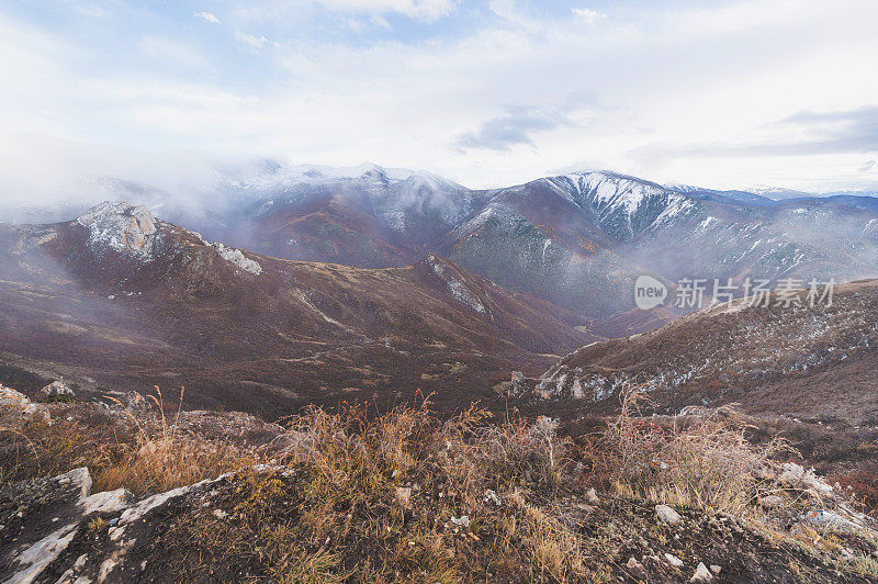 亚洲景观有山峰、小山、森林和田野，天空多云。