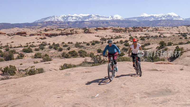 女性山地自行车手在早上爬上滑石小径