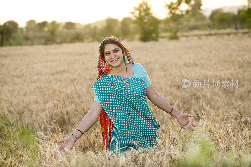 幸福的农村妇女在农田里伸开双臂