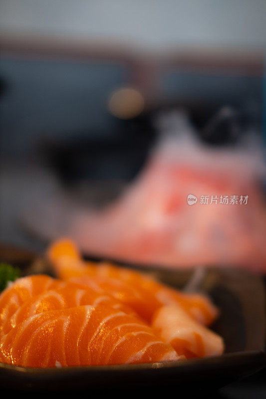 三文鱼生鱼片。黑色的餐桌上放着日本传统菜肴。近距离