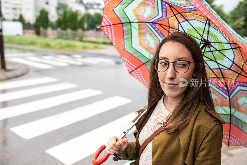 一名年轻女子撑着雨伞在秋雨中漫步