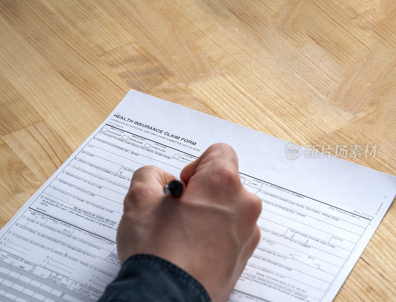 男人手填写健康保险表格在一张桌子上库存照片