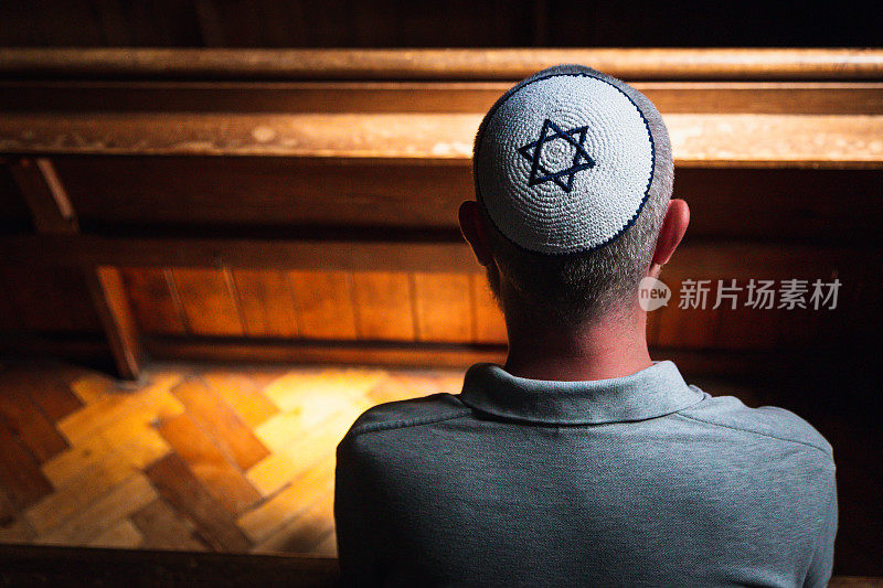 年轻的犹太男子戴着骷髅帽在会堂里祈祷