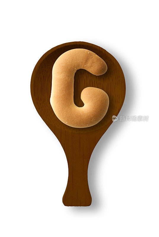 孤立的照片的大写字母饼干G上的木勺，在白色的背景