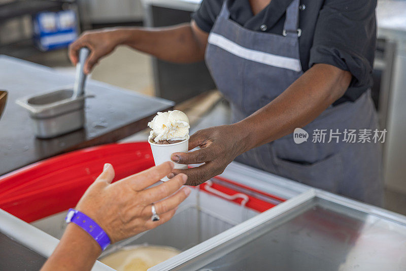 餐厅工作人员将一杯冰淇淋递给游客的特写镜头。库拉索岛。