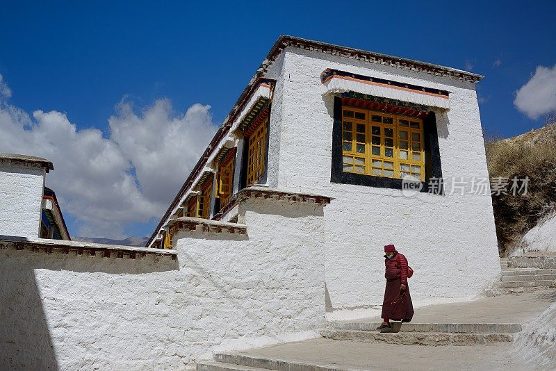 拉萨，中国——2024年3月27日:一名祈福者正经过塞拉寺的藏式民居。