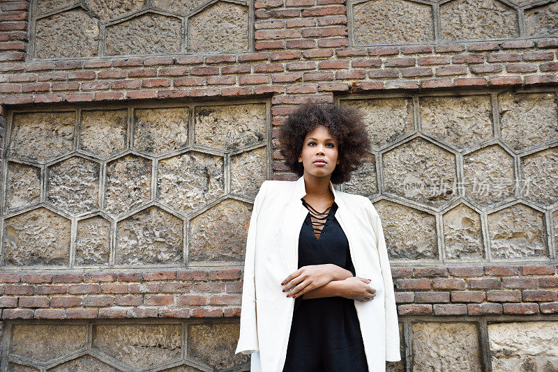 年轻的黑人妇女站在城市的背景与非洲式发型。