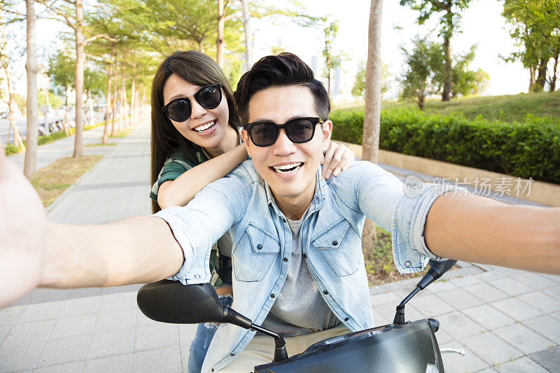 快乐的年轻夫妇骑着滑板车自拍