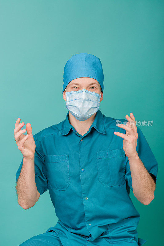 男外科医生戴着面具看着蓝色背景的摄像机，特写