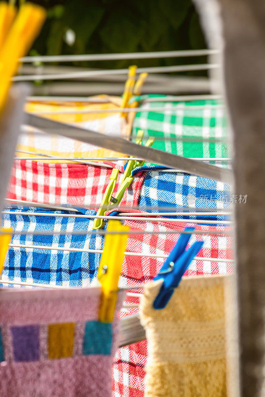 花园里的晒衣绳上晒着毛巾、方形图案的多色餐巾