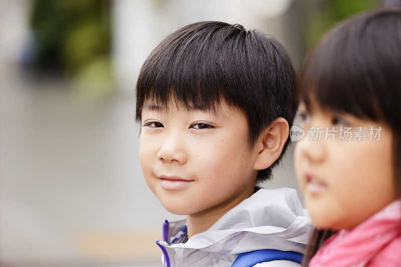 两个日本小孩站在城市街道上