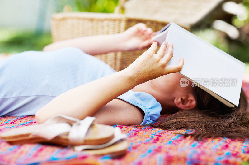 躺在地毯上用书蒙住脸的女人