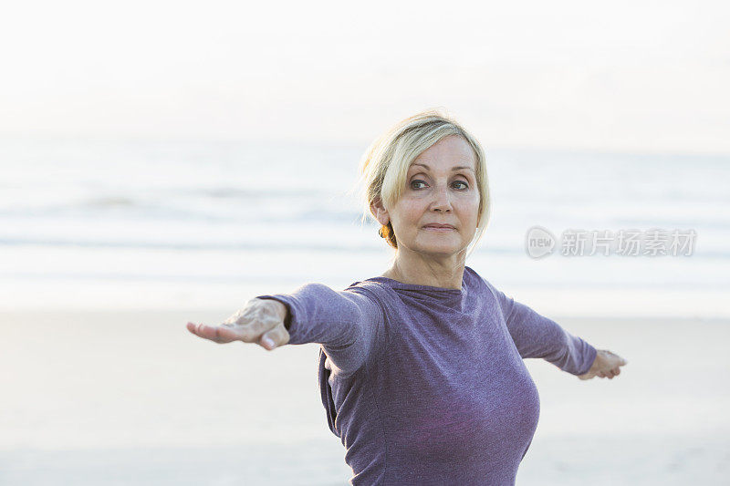 成熟的女人在海滩上做瑜伽