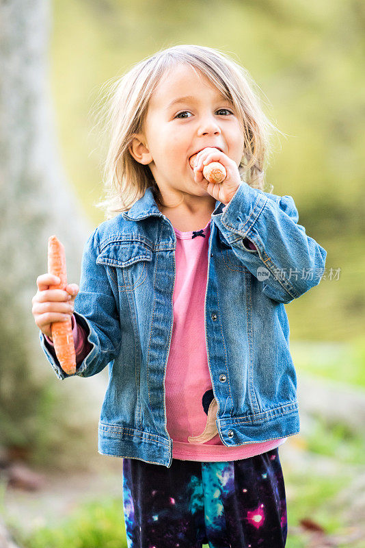 小女孩在公园里吃胡萝卜