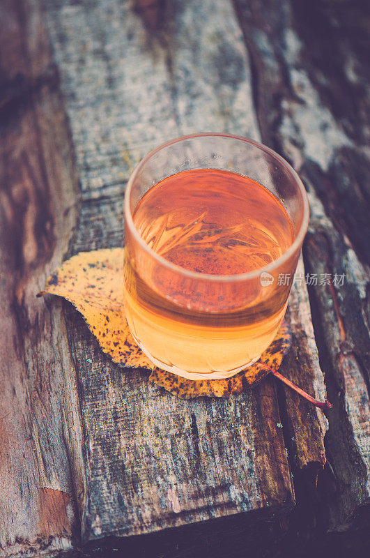 苹果汁杯放在木头上，用叶子做杯垫