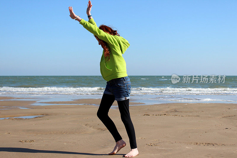 一个女孩在海滩上锻炼，准备做侧手翻