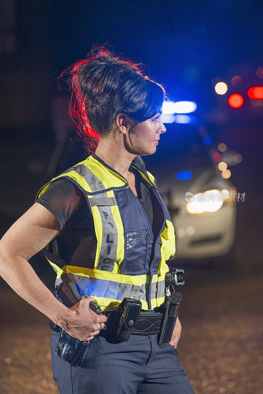 晚上有女警察在街上巡逻，后面是警车
