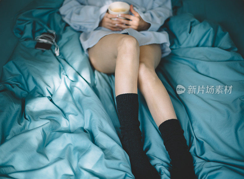 床上拿着咖啡杯的女人