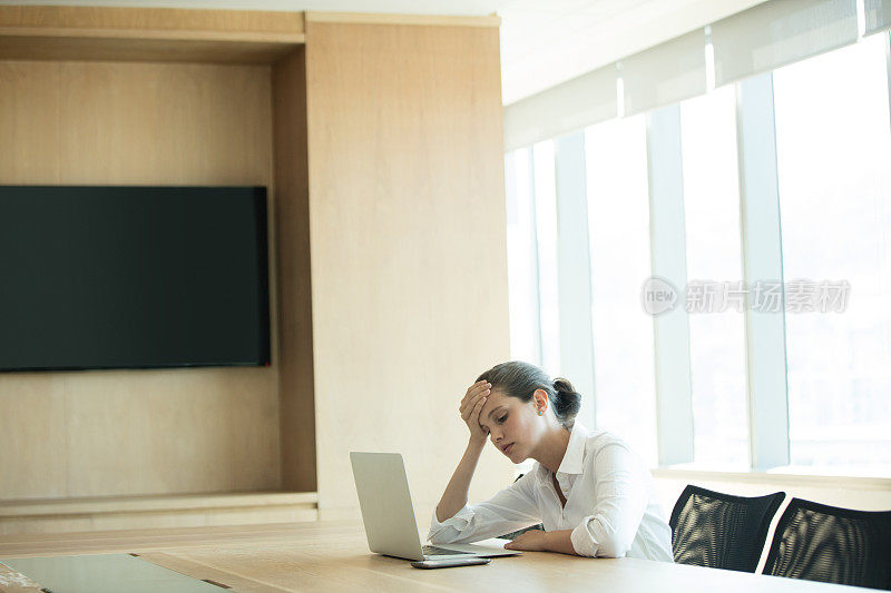 忧心忡忡的女商人在会议室里使用笔记本电脑