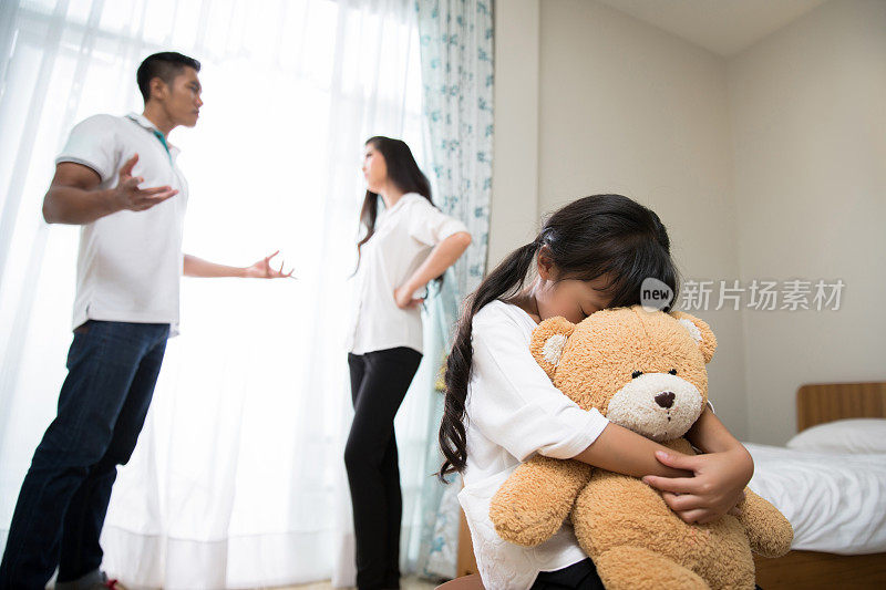 父母吵架女儿感到压力大。她抱着一只泰迪熊哭了起来