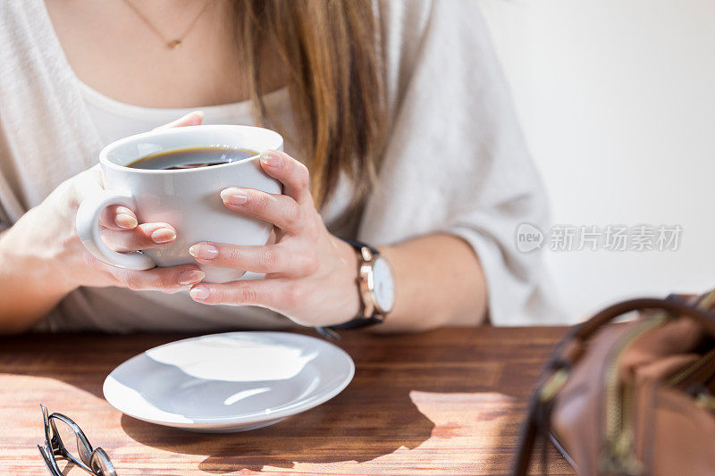 特写镜头，一个不认识的女人拿着咖啡杯在桌子上