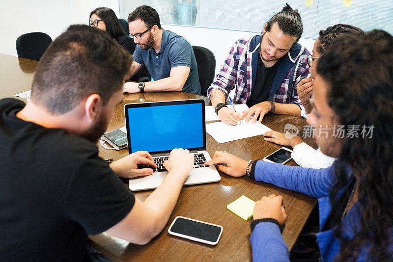 年轻的商业团队在创意办公室会议室讨论时使用笔记本电脑