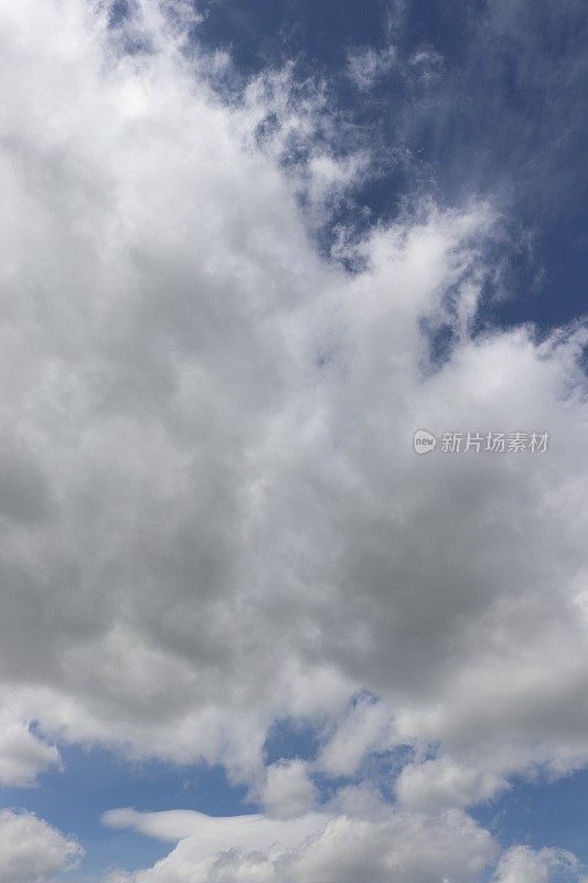 蓝色天空映衬着蓬松、缕缕白云的特写