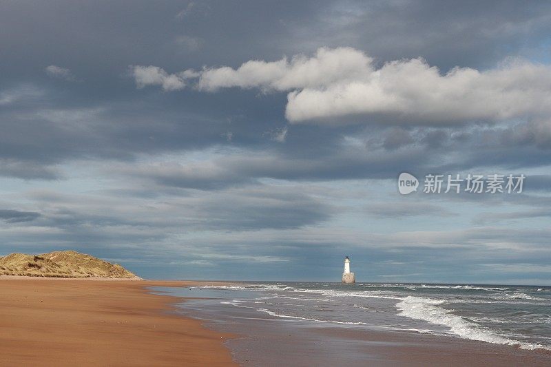 沙丘、海滩和大海上的云，远处有灯塔