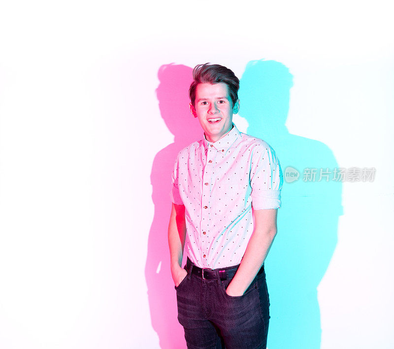 英俊的年轻人站在白色的墙壁和彩色的影子