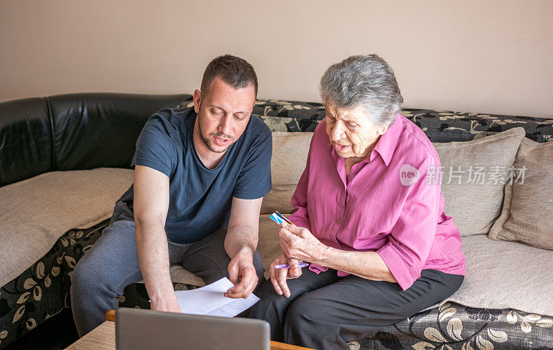 年轻男子帮助年长妇女使用笔记本电脑