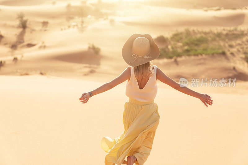 一个年轻的女人从沙丘顶上奔向日出。梅尔祖加(撒哈拉)沙漠的日出。